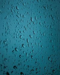 Full frame shot of raindrops on blue glass