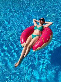 High angle view of woman lying on pool raft in swimming pool