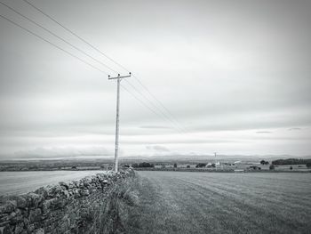 Electricity pylon on field against sky