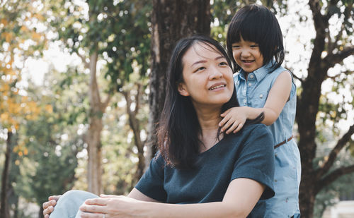 Portrait of a smiling young woman against trees