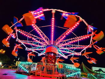 Low angle view of illuminated ferris wheel against sky at night