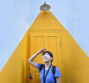 Smiling woman looking up while standing against door