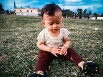 Cute boy sitting on field