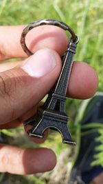 Cropped hand holding eiffel tower key ring on sunny day