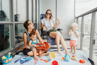 Young mothers spending time together with children babies on balcony at home. staycation 