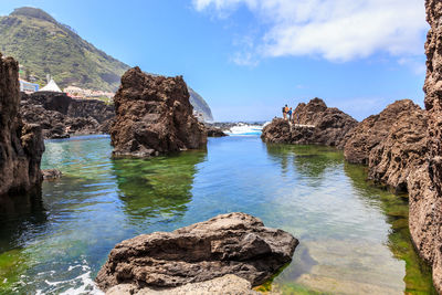 Scenic view of sea by rock formation against sky