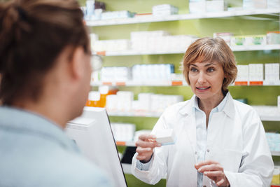 Female pharmacist explaining customer over medicine in pharmacy