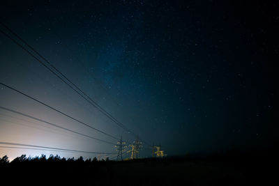 Low angle view of silhouette electricity pylon against sky at night