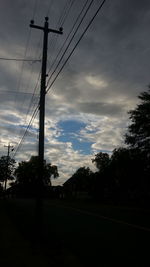 Low angle view of electricity pylon against cloudy sky