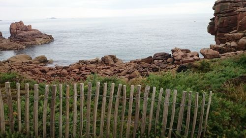 Scenic view of rocks by sea against sky