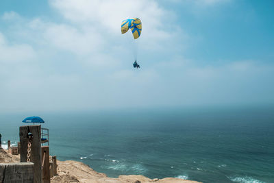 Person paragliding against sea and sky