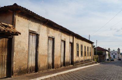 Exterior of old building by road against sky