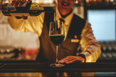 Midsection of man drinking beer in glass