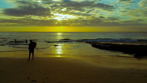 Silhouette man standing on beach against sky during sunset