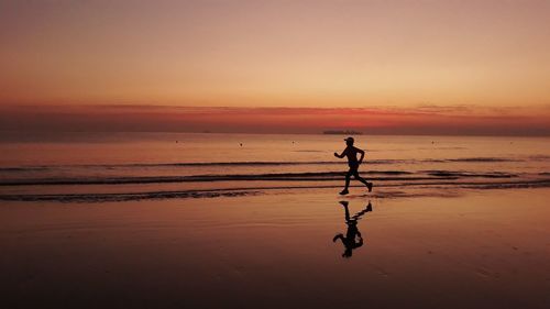 Silhouette person on beach against sky during sunset