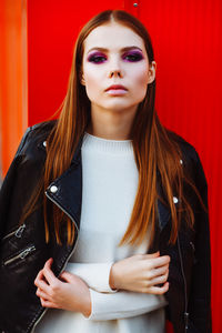 Portrait of beautiful young woman against red wall