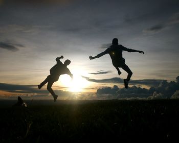 Silhouette male friends jumping against sky during sunset