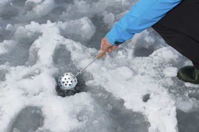 Low section of man ice fishing