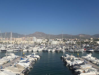 Sailboats moored at harbor against clear blue sky