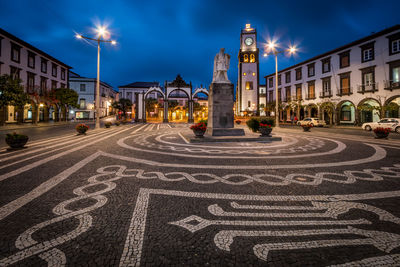 Street lights on road against buildings at night