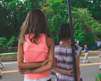 Rear view of siblings standing against trees