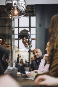 Portrait of bald businessman sitting by female colleague in meeting room