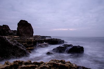 Scenic view of rocks in sea against sky