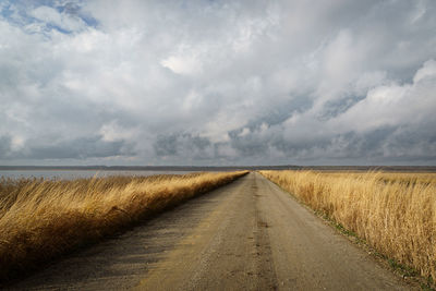 Road amidst field against sky