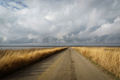 Road amidst field against sky