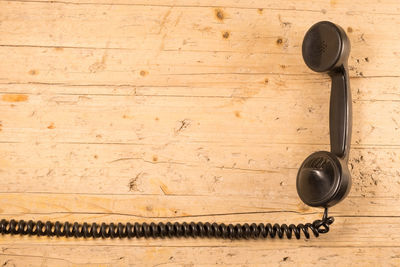 Directly above shot of black telephone receiver on wooden table