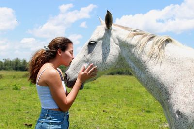 Side view of woman kissing horse at farm