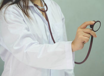 Midsection of woman wearing stethoscope and lab coat