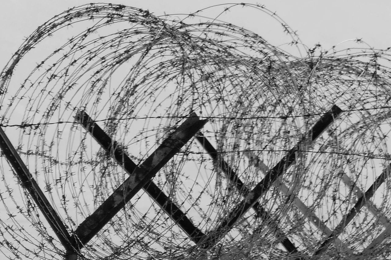 CLOSE-UP OF BARBED WIRE AGAINST SKY