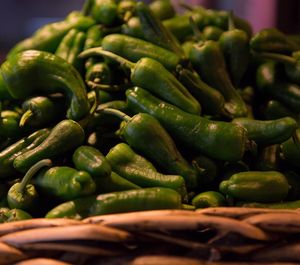 Close-up of green chili peppers in basket for sale at market