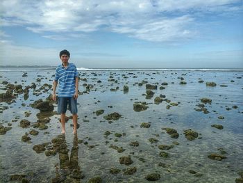 Full length of man standing on beach against sky