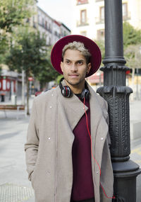 Young man with headphones and red hat  standing in city