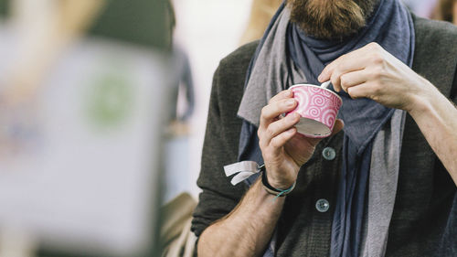 Midsection of man holding disposable cup