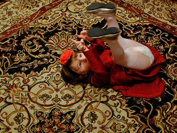 High angle view of girl gesturing while lying on carpet