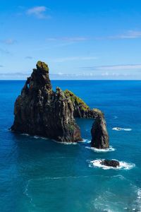 Rock formation in sea against blue sky