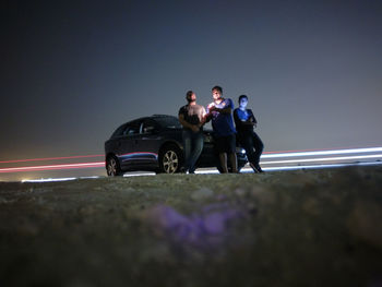 Two men on car in city at night