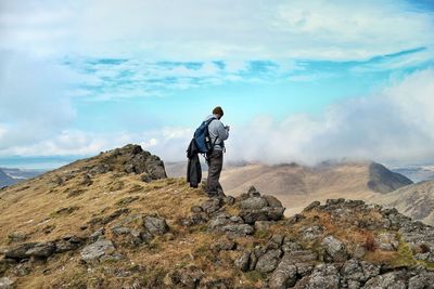 Rear view of man standing on mountain against sky