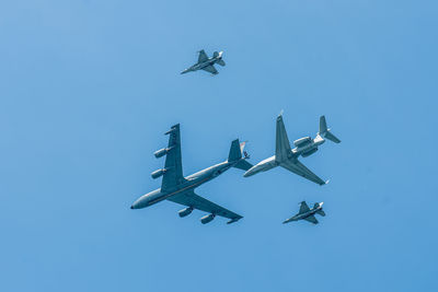 Low angle view of airplane flying against clear blue sky