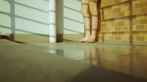 Low section of woman standing on tiled floor at home