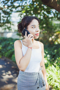 Young woman standing against trees
