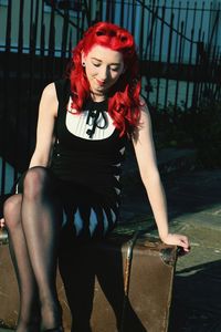 Smiling redhead woman sitting on old-fashioned suitcase
