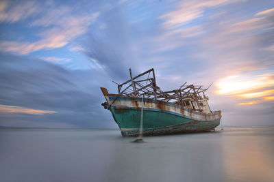 Boat in sea against sky during sunset