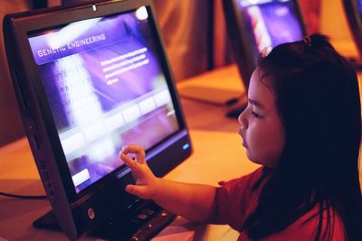 Side view of girl using computer on table in