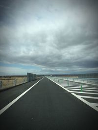 Empty road against cloudy sky
