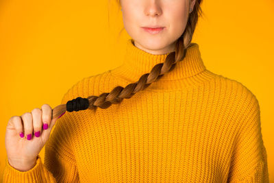 Midsection of woman with braided hair against yellow background