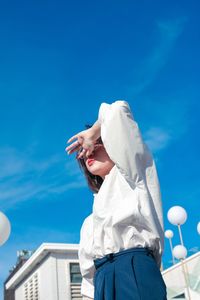 Low angle view of woman standing against blue sky